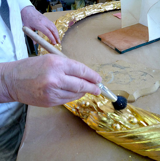 La grande couronne de lauriers a été sculptée puis dorée à la feuille d'or. La grande couronne de lauriers a été sculptée puis dorée à la feuille d'or.