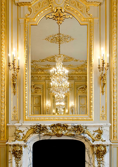 The dining room chandeliers reflect to infinity in the chimneys' mirrors.